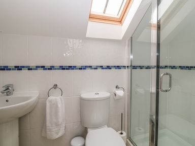 A bathroom with a sink toilet towel and shower under a skylight window at Atlantic Reach in Widemouth Bay