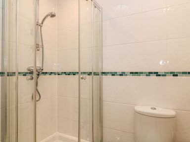 A shower enclosure with glass doors and a toilet in a tiled bathroom at Atlantic Reach in Widemouth Bay