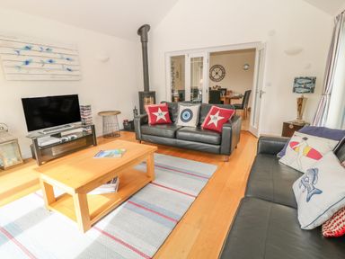 A living room with two black leather sofas a wooden coffee table and a flat screen tv at Atlantic Reach in Widemouth Bay