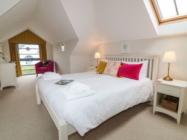 A bedroom with a white bed with pillows towels and bedside tables with lamps at Atlantic Reach in Widemouth Bay