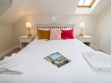 A bedroom with a double bed white bedside tables and lamps at Atlantic Reach in Widemouth Bay