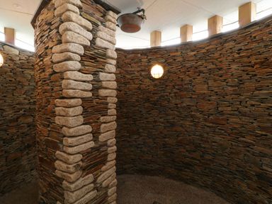 An interior space with circular stone walls and a central stone column at Atlantic Reach in Widemouth Bay