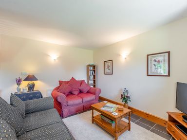 A living room with sofas a coffee table a lamp and pictures on the walls at Cwmdu Cottage in Cwm-Cou near Newcastle Emlyn
