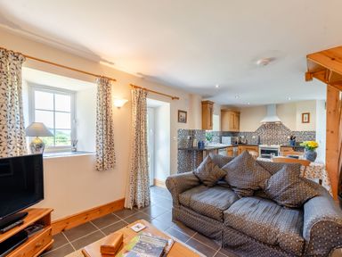 An open-plan living room and kitchen with a sofa and dining table at Cwmdu Cottage in Cwm-Cou near Newcastle Emlyn