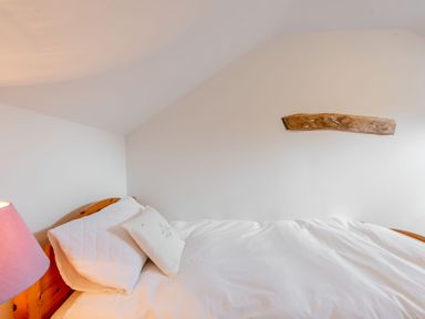 A bedroom with a bed with white bedding and pillows and a wooden headboard with a lamp on the side at Cwmdu Cottage in Cwm-Cou near Newcastle Emlyn