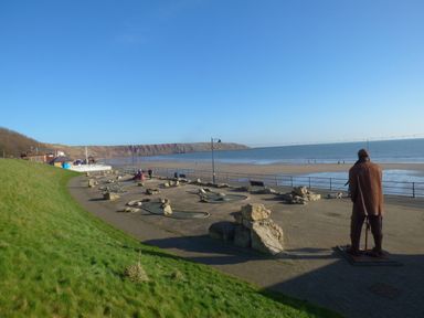A seaside promenade with mini golf course and statue overlooking a sandy beach at Sunny Bay The Bay near Filey