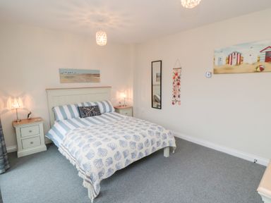 A bedroom with a bed between two nightstands a wall mirror and paintings at Sunny Bay The Bay near Filey