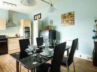 A kitchen with a black dining table set with plates and glasses with black chairs at Westgate Retreat in Hunstanton
