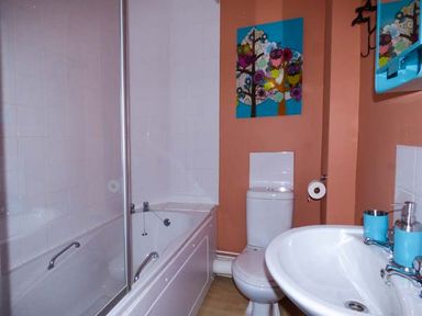 A bathroom with a bathtub toilet and sink with blue accessories and owl wall art at Westgate Retreat in Hunstanton