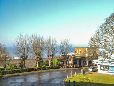 A street view with bare trees parked cars and buildings near the seaside at Westgate Retreat Hunstanton