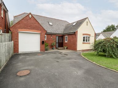 A brick and stucco house with a garage and driveway and a small garden at Hurst Green in Ewyas Harold near Hereford