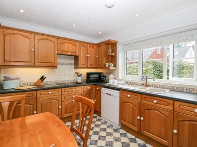 A kitchen with wooden cabinets a dining table and chairs a dishwasher microwave and a window at Hurst Green in Ewyas Harold near Hereford