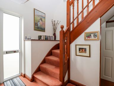 A stairway with orange carpet and wooden banister beside a frosted glass door with framed paintings on the wall at Hurst Green in Ewyas Harold near Hereford