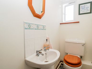 A bathroom with a sink, mirror, window, toilet with wooden seat and framed picture on the wall at Hurst Green in Ewyas Harold near Hereford