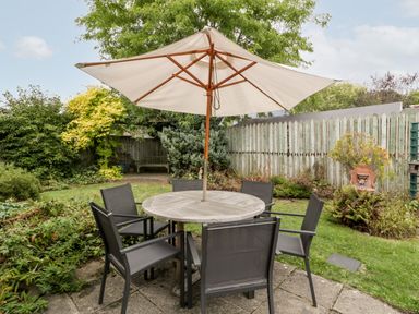 A garden with a round table and six chairs under a large umbrella at Hurst Green in Ewyas Harold near Hereford