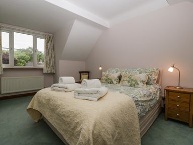 A bedroom with a bed covered with floral bedding and folded towels on top at Hurst Green in Ewyas Harold near Hereford