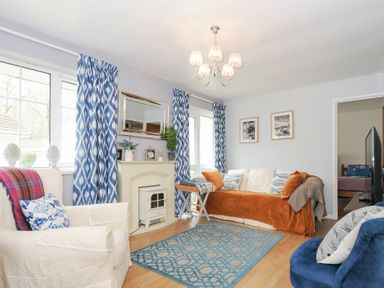 A living room with armchairs sofa a rug and blue patterned curtains at No 1 The Heathers Rosecraddoc Lodge near Liskeard