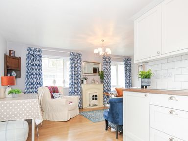 A living room with armchairs a dining table and blue patterned curtains at No 1 The Heathers Rosecraddoc Lodge near Liskeard