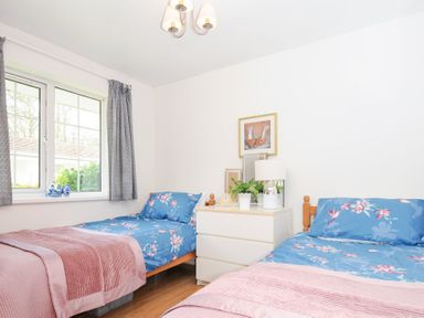 A bedroom with two single beds with blue floral bedding and pink blankets at No 1 The Heathers Rosecraddoc Lodge near Liskeard
