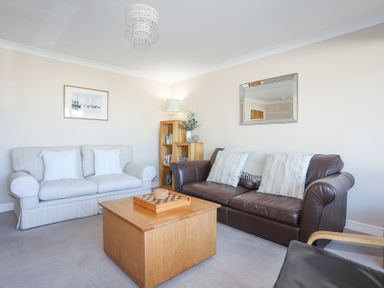 A living room with two sofas a wooden coffee table a bookshelf and a wall mirror at Tegfan in Trearddur Bay