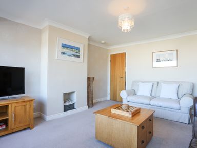 A living room with a sofa table television and fireplace at Tegfan in Trearddur Bay