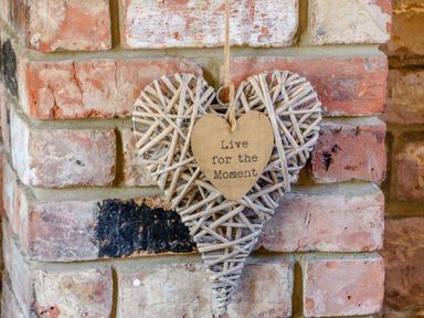 A heart-shaped wicker decoration hanging on a brick wall with a smaller wooden heart that says Live for the Moment at Goathland Cottage in Ruswarp near Whitby