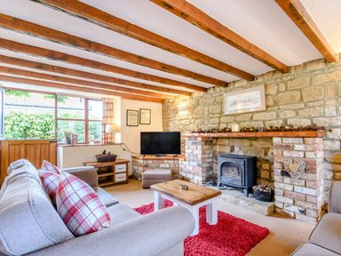 A living room with exposed wooden beams and stone fireplace at Goathland Cottage Ruswarp near Whitby