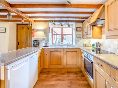 A kitchen with wooden cabinets white appliances and a window at Goathland Cottage Ruswarp near Whitby