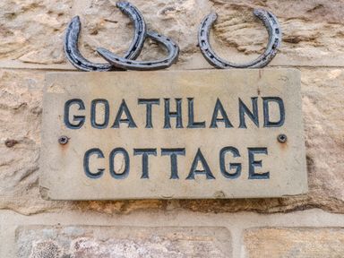 A stone plaque with Goathland Cottage text and three horseshoes above on a stone wall at Goathland Cottage Ruswarp near Whitby