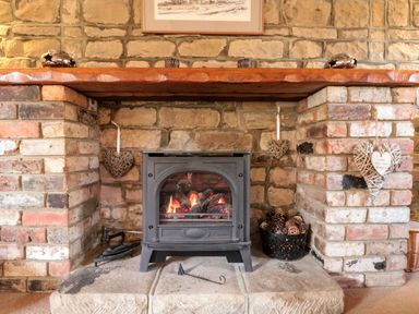 A brick fireplace with a wood burning stove and decorative heart ornaments at Goathland Cottage in Ruswarp near Whitby