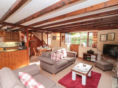 A living room with sofas cushions coffee table dining table and kitchen area at Goathland Cottage in Ruswarp near Whitby