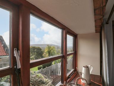 A window with a garden view and hills in the background at Goathland Cottage in Ruswarp near Whitby