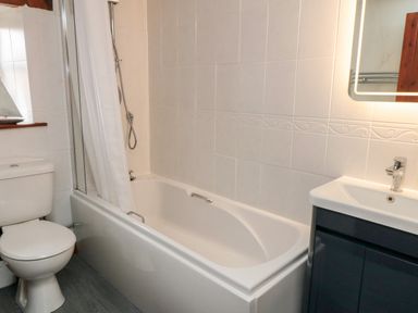 A bathroom with a bathtub shower combination toilet and sink unit at Goathland Cottage in Ruswarp near Whitby