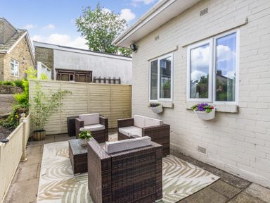 An outdoor patio with wicker furniture and flower pots on the wall at Bracken Barn Cottage in Widdrington near Amble