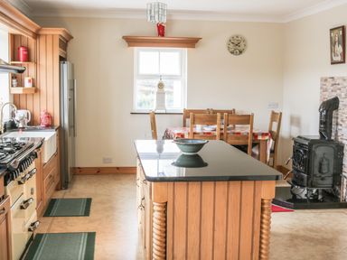 A kitchen with wooden cabinets a black countertop island a dining table with wooden chairs and a stove at McGuire's Cottage Barnatra County Mayo