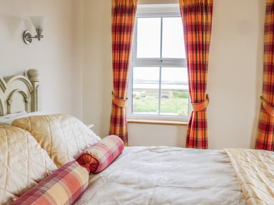 A bedroom with a bed and patterned curtains by a window at McGuire's Cottage Barnatra County Mayo