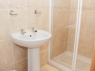 A bathroom with a white pedestal sink and a glass-enclosed shower at McGuire's Cottage in Barnatra County Mayo