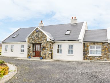 Exterior view of a single-story house with stone and white walls and a gray roof at McGuire's Cottage Barnatra County Mayo