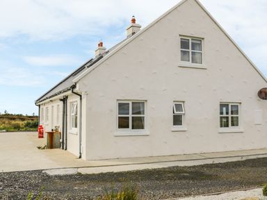 Exterior of a white house with multiple windows and chimneys in a rural area at McGuire's Cottage Barnatra County Mayo