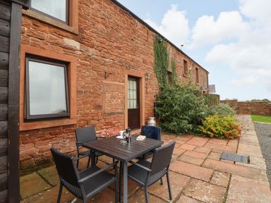 An outdoor area with a table and chairs at Hayloft Cottage in Bolton Low Houses