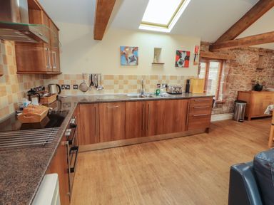 A kitchen with wooden cabinets and a sink at Hayloft Cottage Bolton Low Houses