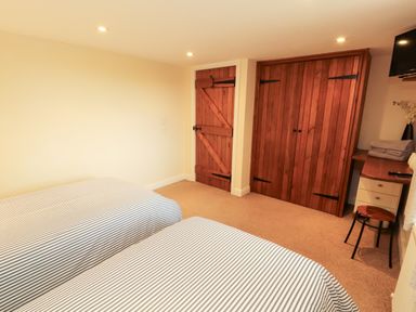 A bedroom with two beds and wooden furniture at Hayloft Cottage Bolton Low Houses