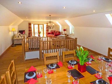 A dining area with set tables and a sitting area with sofas and a television at Brynhir Farm in Howey near Llandrindod Wells