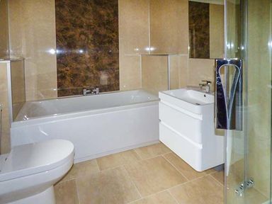 A bathroom with a toilet bathtub sink and glass shower door at Brynhir Farm in Howey near Llandrindod Wells