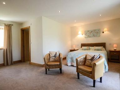 A bedroom with two armchairs and a bed at Brynhir Farm in Howey near Llandrindod Wells