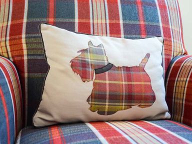 A cushion with a dog silhouette on a plaid armchair at Brynhir Farm in Howey near Llandrindod Wells