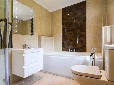 A bathroom with a white bathtub shower toilet and sink with a mirror at Brynhir Farm in Howey near Llandrindod Wells