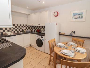 A kitchen with appliances and dining table at Garth Cottage in Haverfordwest