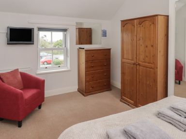 A bedroom with furniture including a television and a wardrobe at Garth Cottage in Haverfordwest