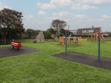 A playground with swings and climbing equipment at Garth Cottage in Haverfordwest